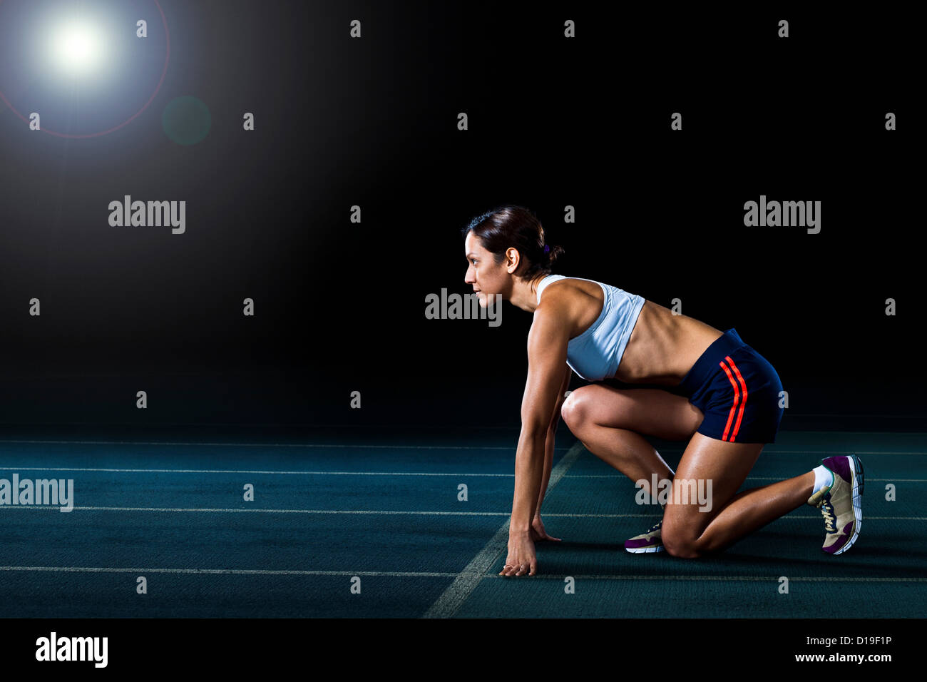 Atleta femminile nella posizione iniziale sulla via di corsa Foto Stock