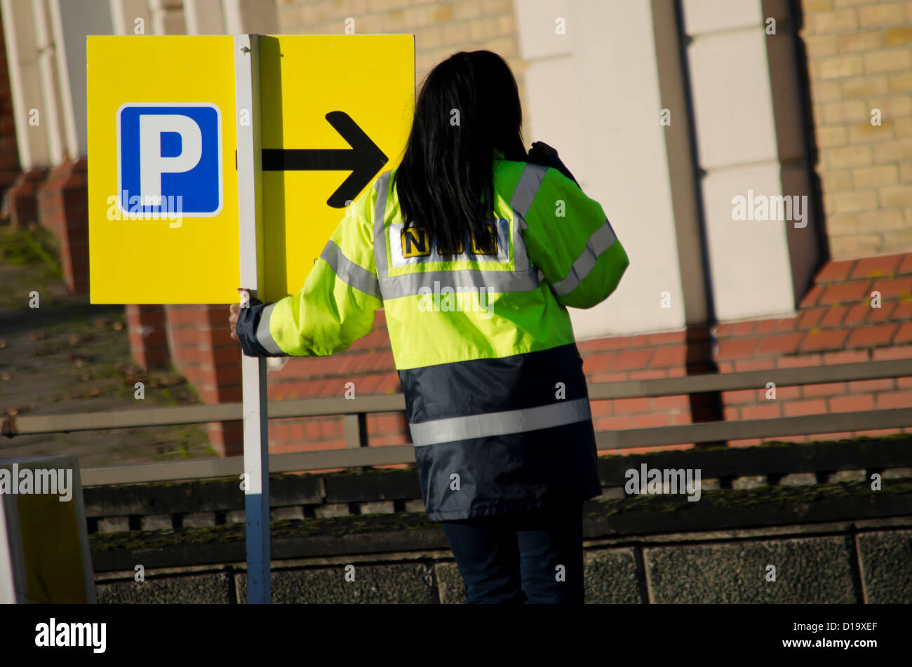 Una donna tenendo un cartello che indica a un parco auto Foto Stock