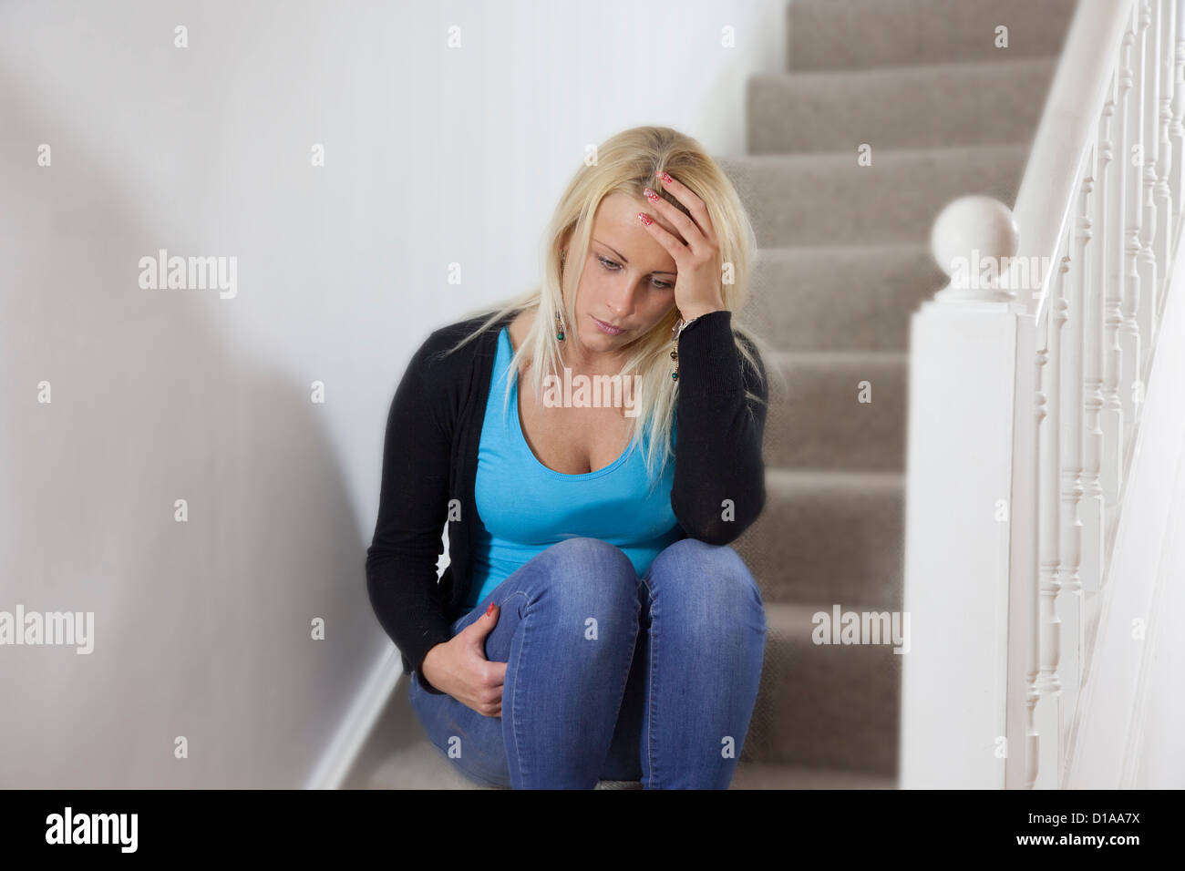 Giovane donna premuto, seduto da solo sulle scale mano sulla testa. La forma del paesaggio. Foto Stock