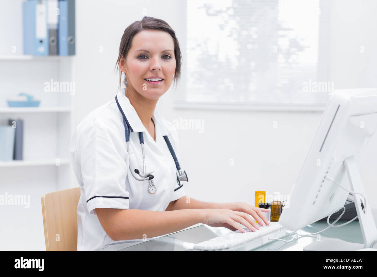 Donna sorridente infermiera utilizzando computer presso la clinica Foto Stock