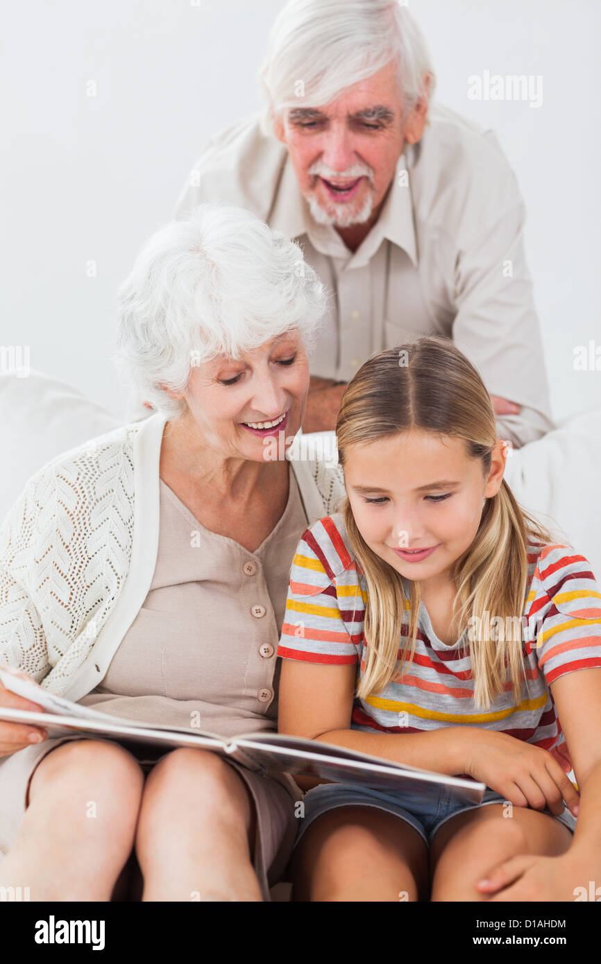 Ragazza sorridente la lettura con i nonni Foto Stock