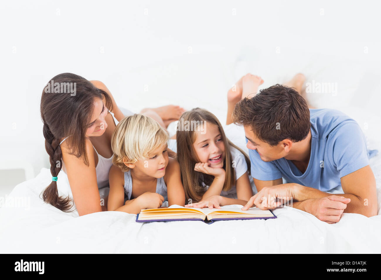 Famiglia libro di lettura sul letto Foto Stock