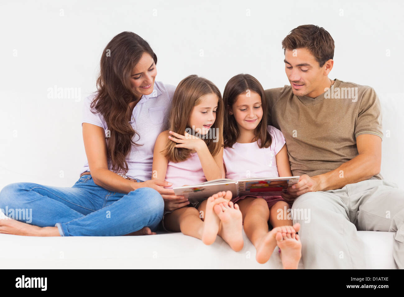 Famiglia la lettura di una storia su un divano Foto Stock