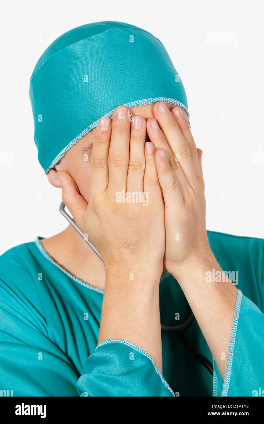 Un maschio ricalcato chirurgo che ricopre la faccia le mani Foto Stock