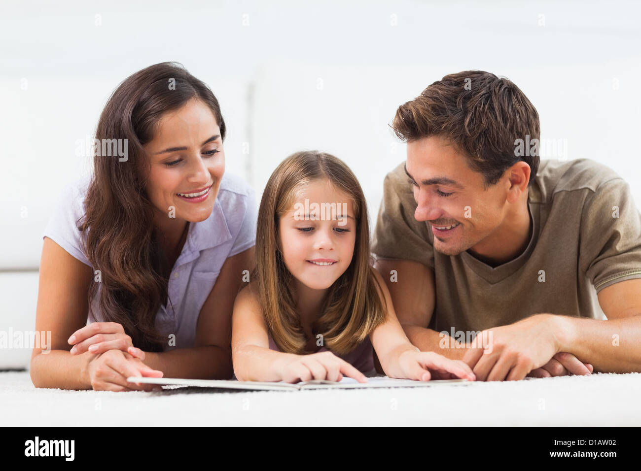 Famiglia giacente su un tappeto con un libro Foto Stock