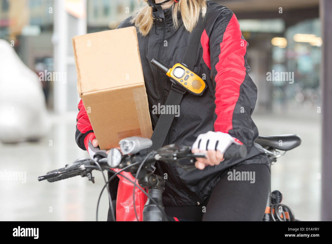 Ciclista femmina con scatola di cartone e Courier Bag su strada Foto Stock