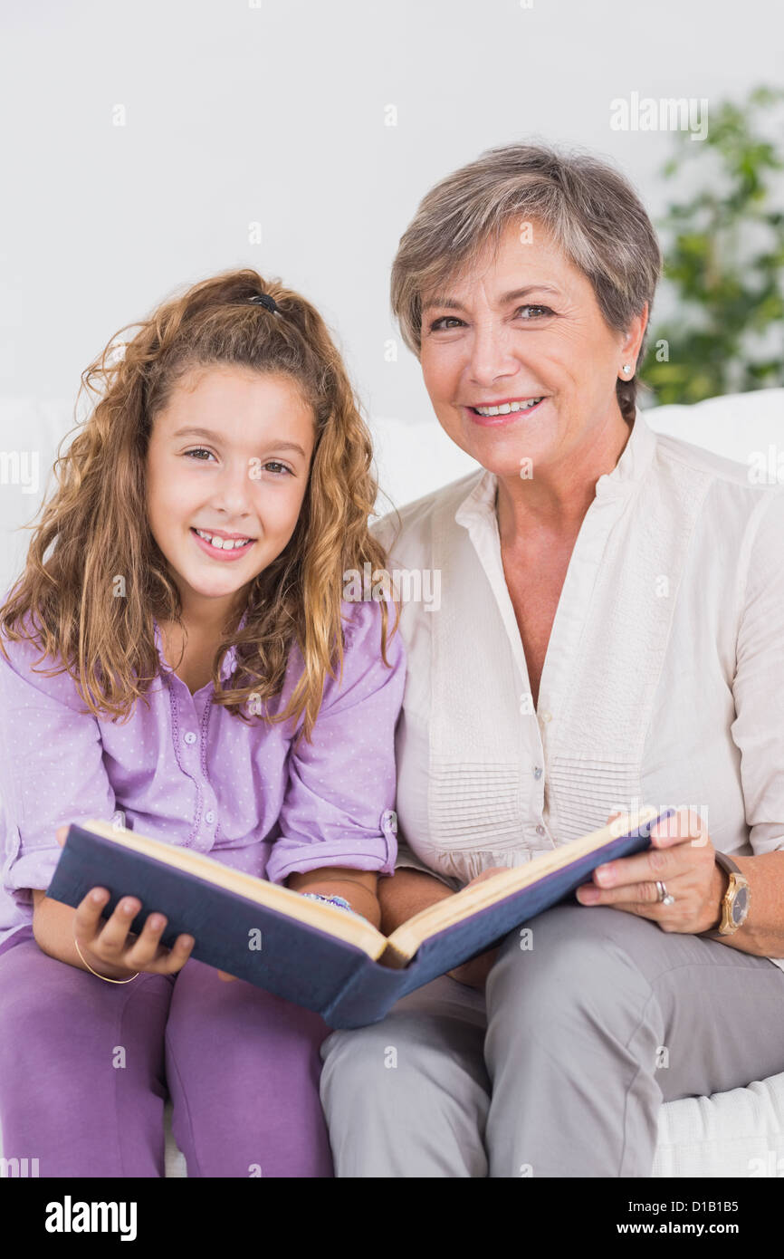 Bambina e la nonna guardando la telecamera con un libro Foto Stock