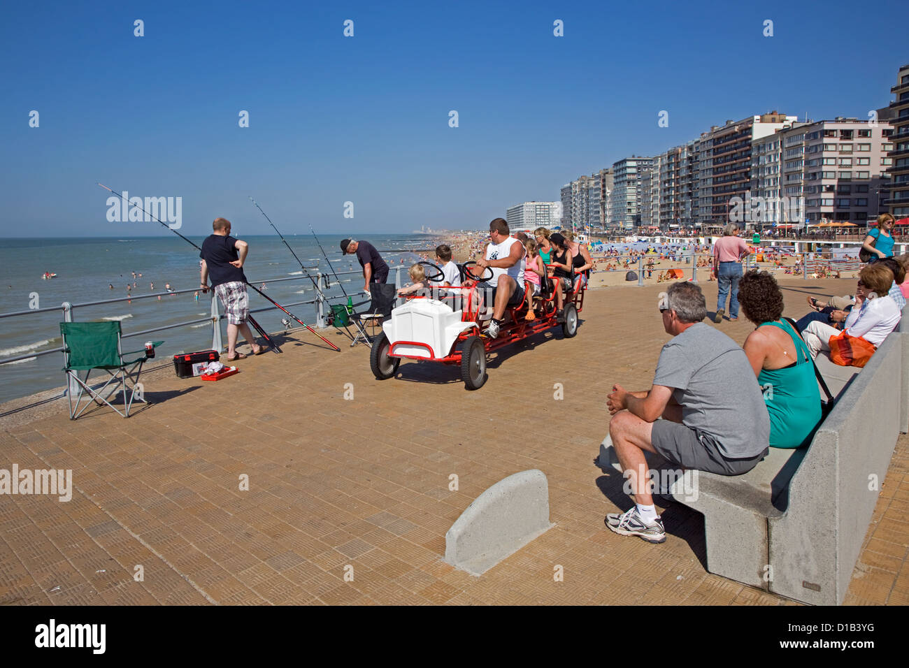 I pescatori di mare e go-cart con i turisti sulla diga del mare promenade di località balneare lungo la costa del Mare del Nord, Belgio Foto Stock