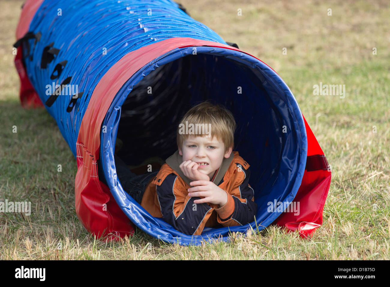 Ragazzo giovane giacente in un tunnel di agilità Foto Stock