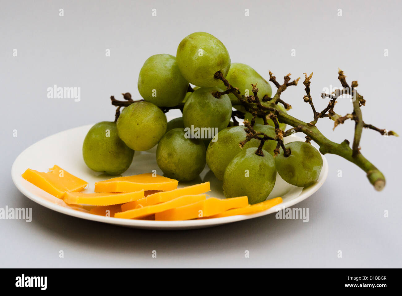 I resti del partito antipasti. Uva e fette di formaggio cheddar su una piccola piastra. Foto Stock