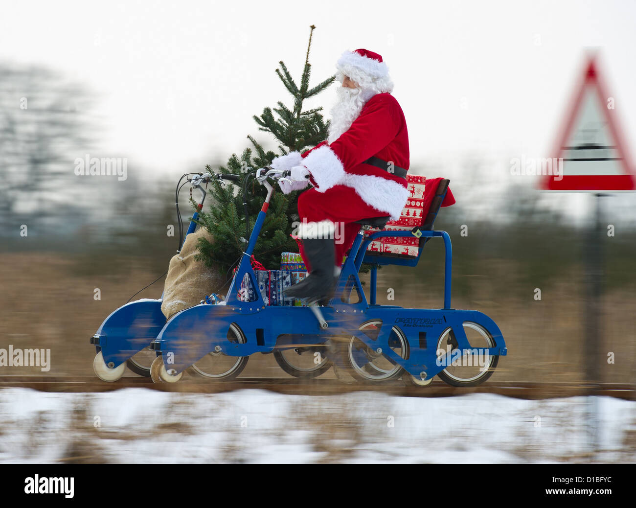 (Illustrazione) Una illustrazione datata 12 dicembre 2012 mostra Santa cavalcando un draisina caricato con doni, deposito sci e un albero di Natale presso la stazione sud del parco di Berlino in Mellensee, Germania. Santa è il test su altri mezzi di trasporto per il Natale nel caso in cui la neve si scioglie. Il fine settimana del terzo e quarto giorno dell'Avvento, la gente sarà in grado di guidare una draisina dell albero di Natale piantagione e di abbattere un albero stessi. Foto: Patrick Pleul Foto Stock