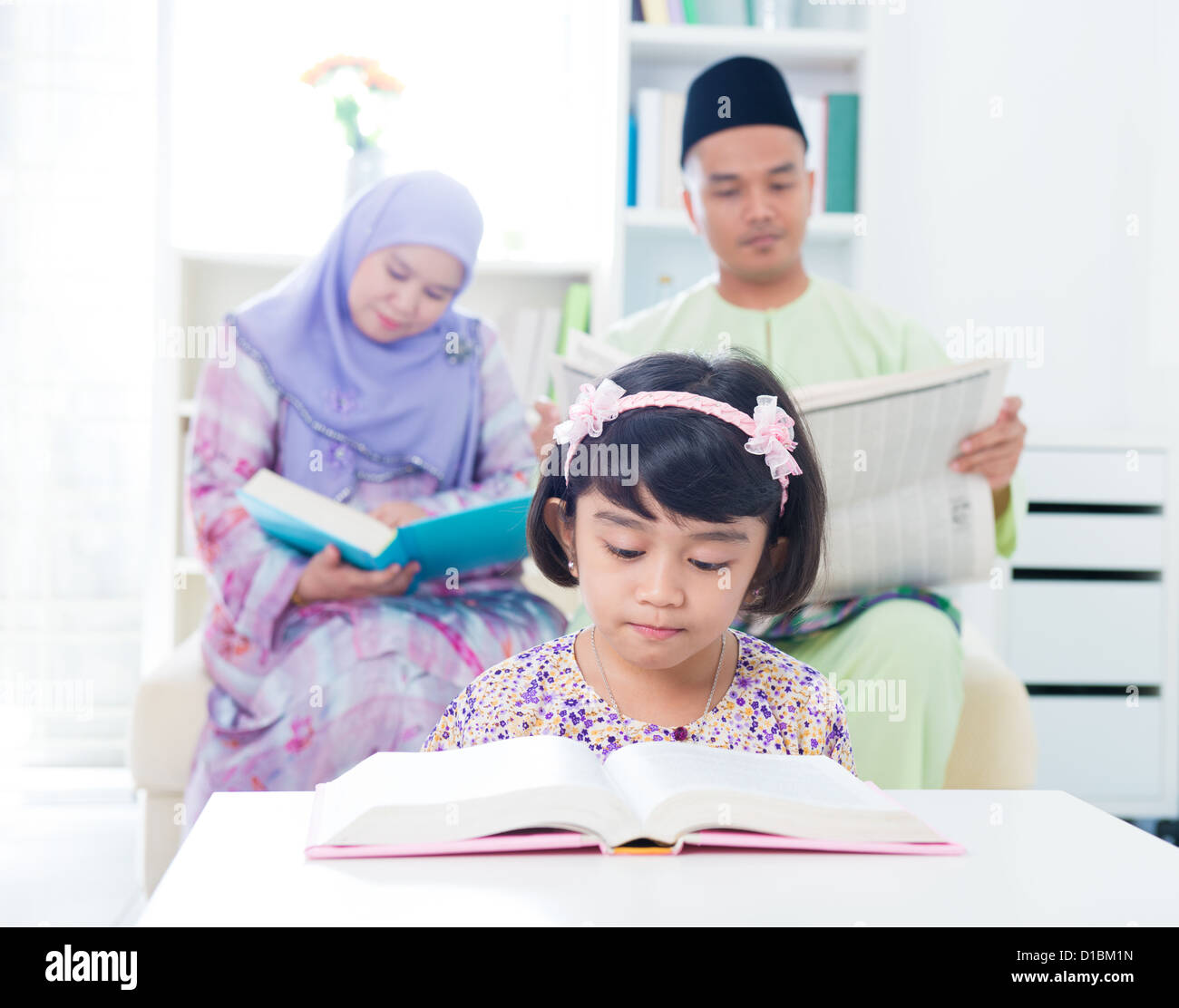 Sud-est asiatico di lettura della famiglia. I genitori musulmani e la lettura del bambino a casa. Foto Stock