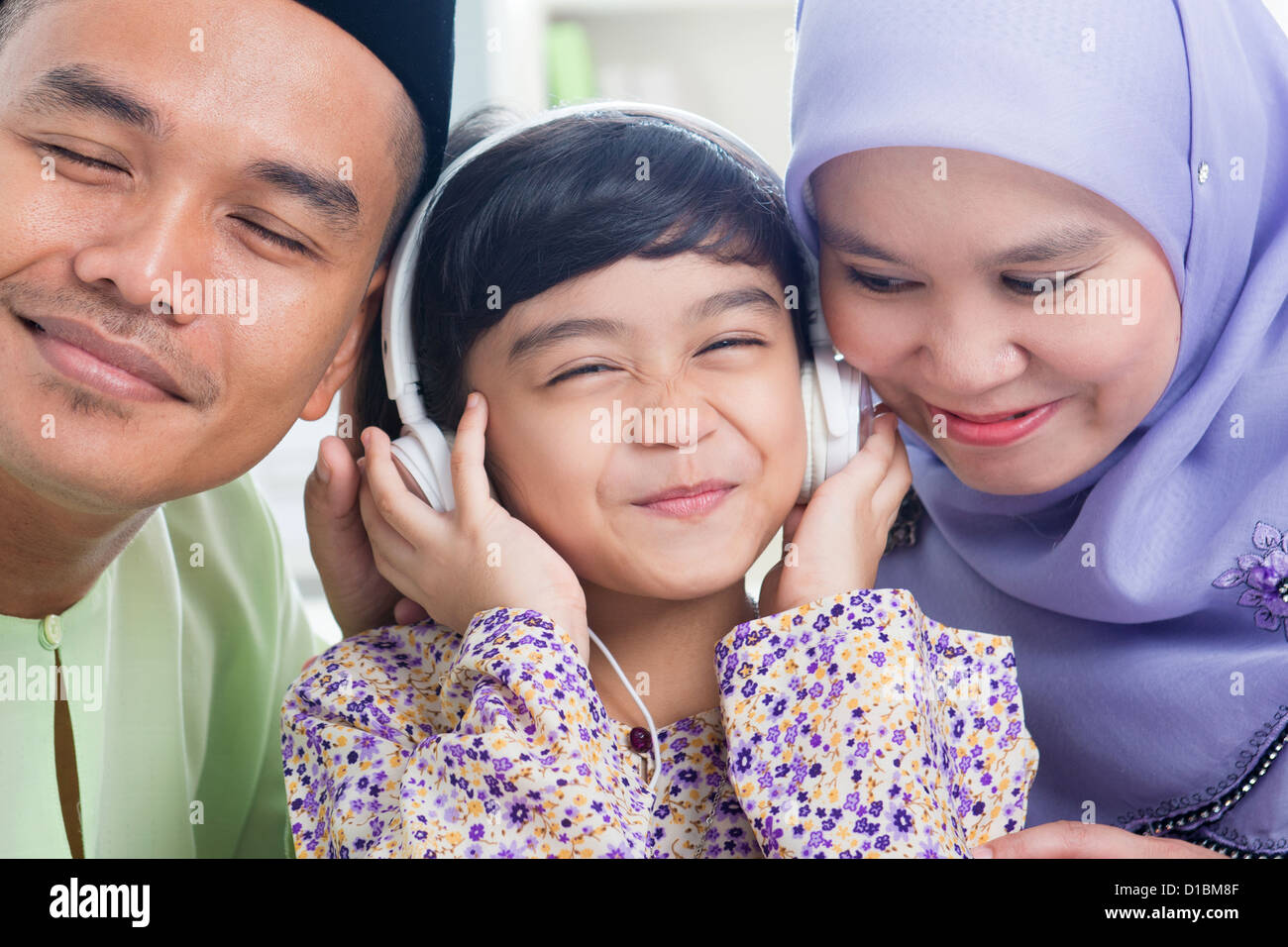 Sud-est asiatico famiglia ascoltare mp3, condividendo le cuffie. Famiglia musulmana stile di vita vivente Foto Stock