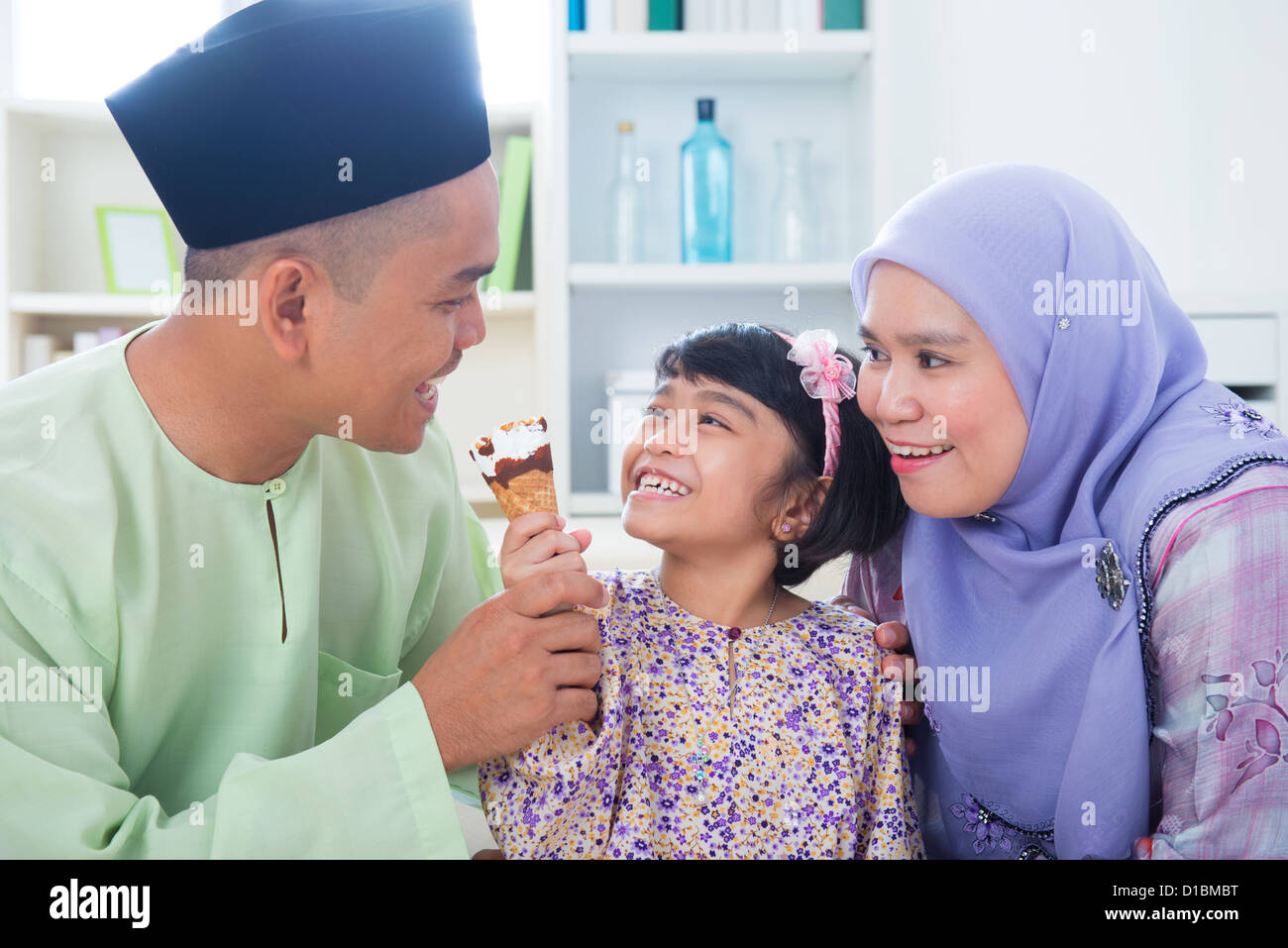 Sud-est ragazza asiatica alimentando il gelato al padre. Malay musulmana lo stile di vita di famiglia Foto Stock