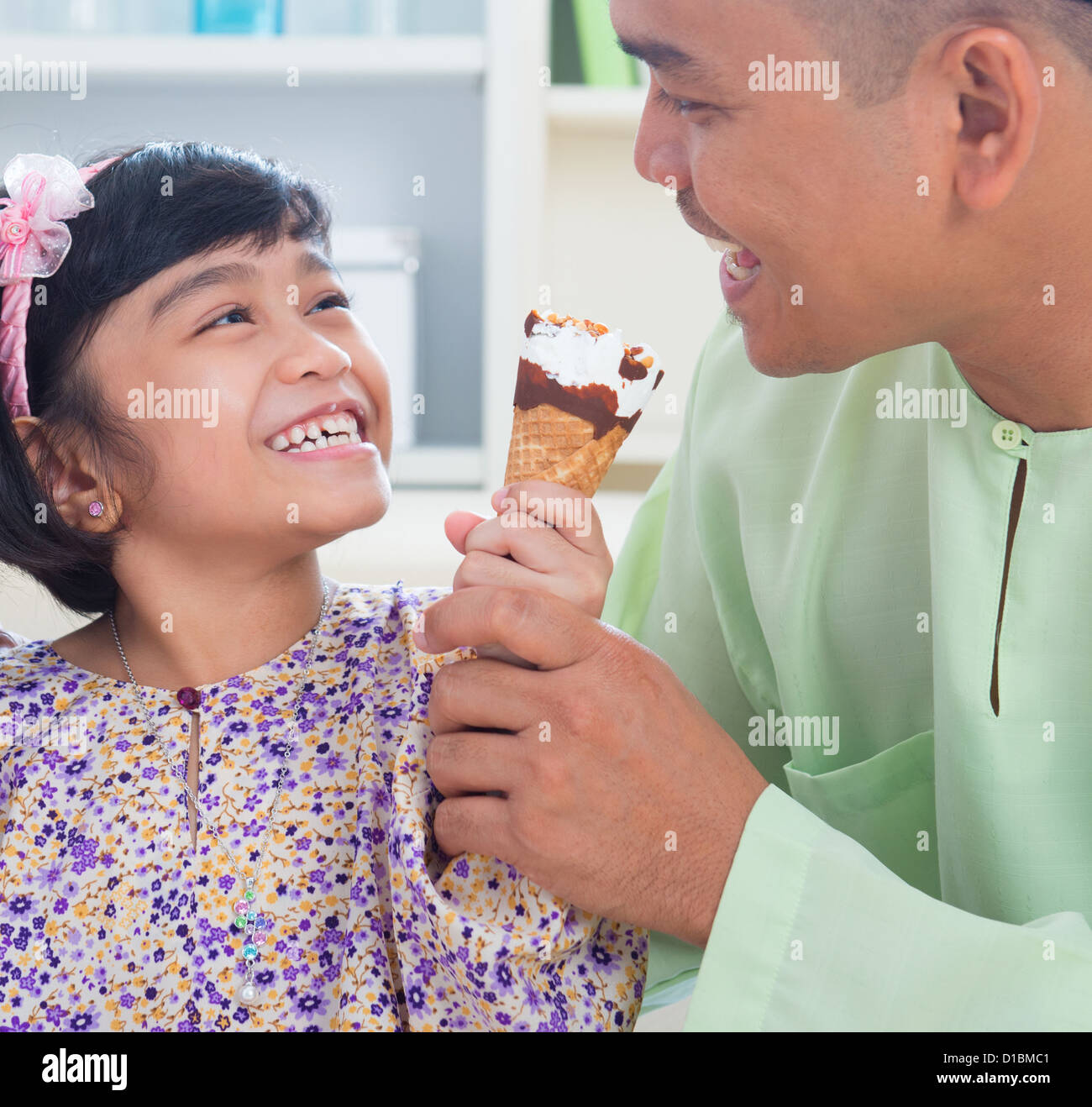 Carino Southeast Asian girl alimentando il gelato al padre. Malay musulmana lo stile di vita di famiglia Foto Stock
