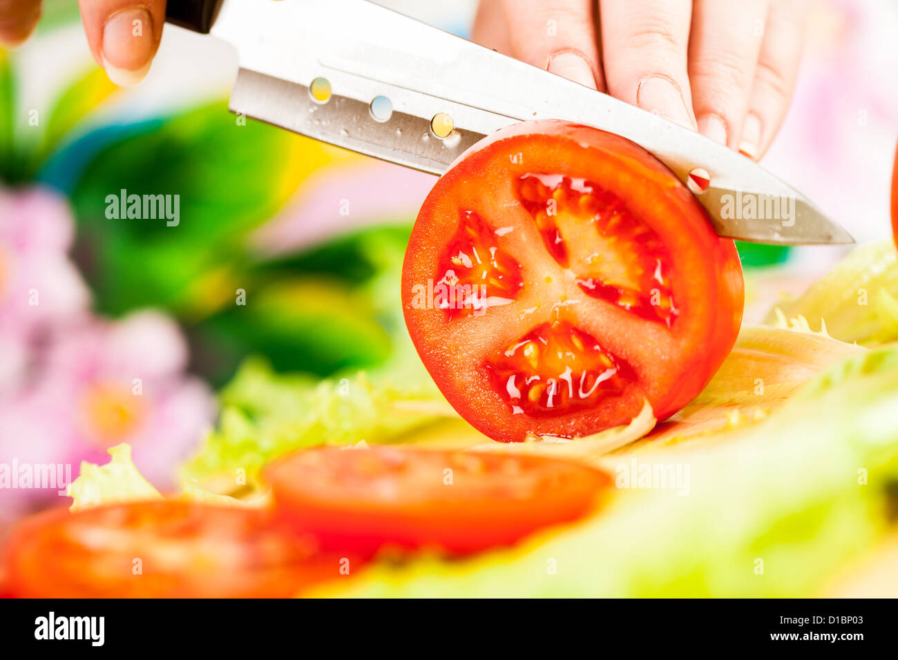 Donna con le mani in mano il taglio di pomodoro, un coltello affilato. Foto Stock