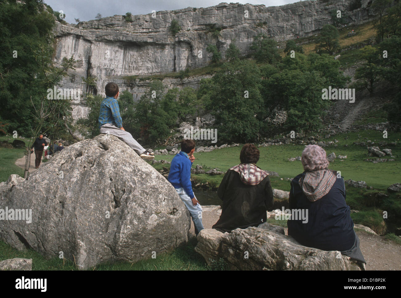 Malham Cove, nello Yorkshire, Inghilterra - una famiglia sedersi e guardare il cove Foto Stock