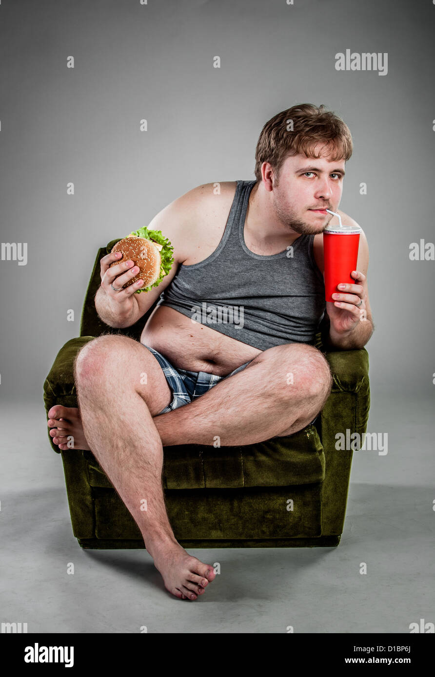 Fat Man mangiare hamburger seduti sulla poltrona Foto Stock