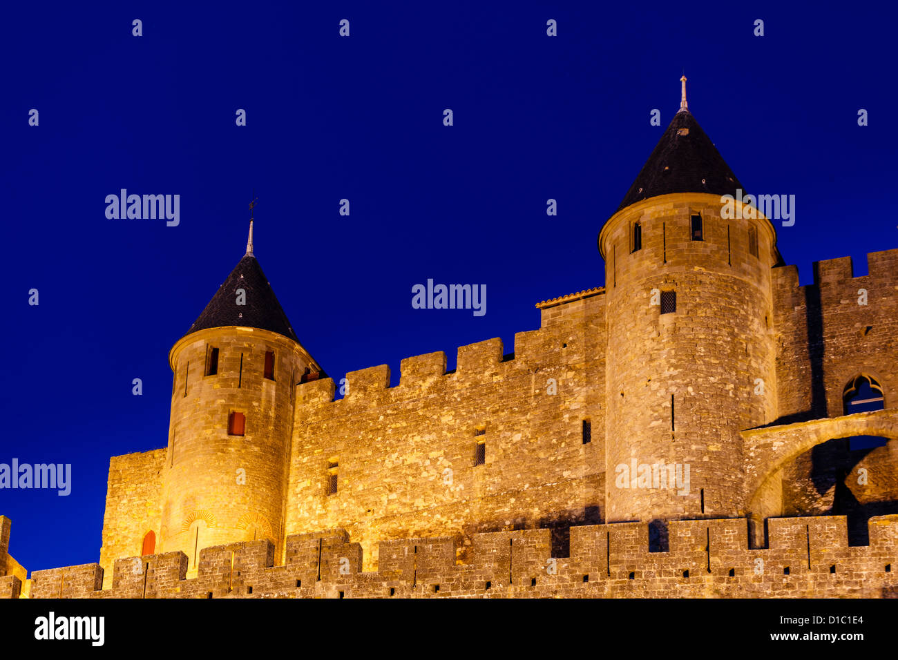 Primo piano della fortezza medievale torri gemelle sulla collina in Carcassonne Francia illuminata al crepuscolo in serata senza nuvole Foto Stock