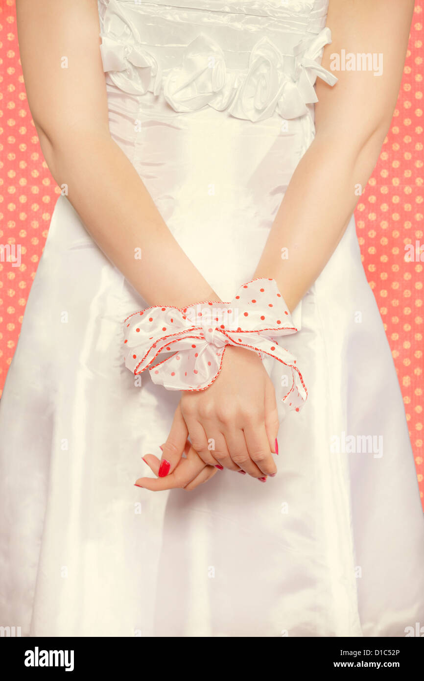 Legato le mani di una ragazza con una polka nastro punteggiata Foto Stock