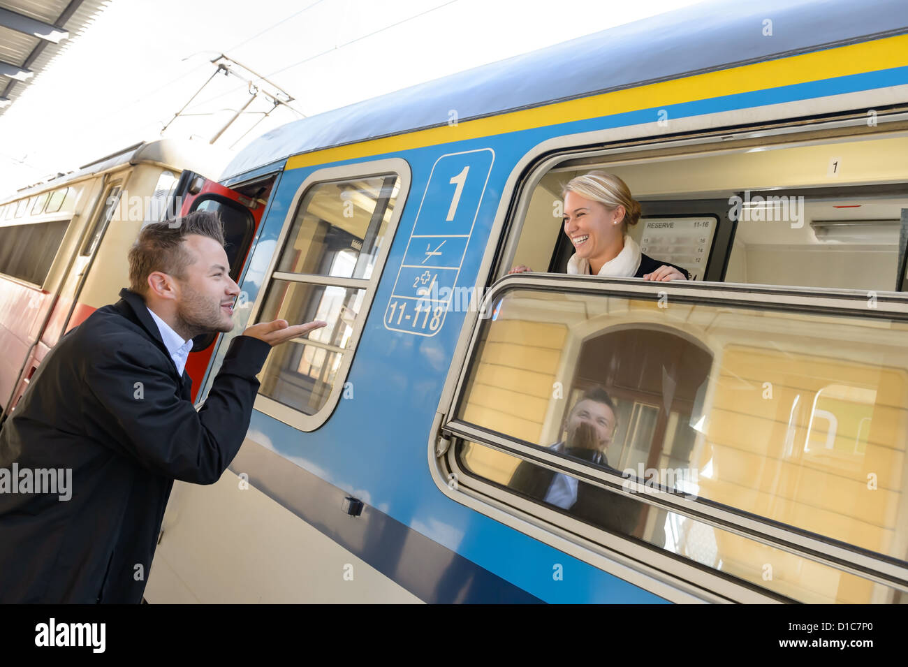 L'uomo soffiando bacio alla donna sul treno felici di lasciare dei " commuters " Foto Stock