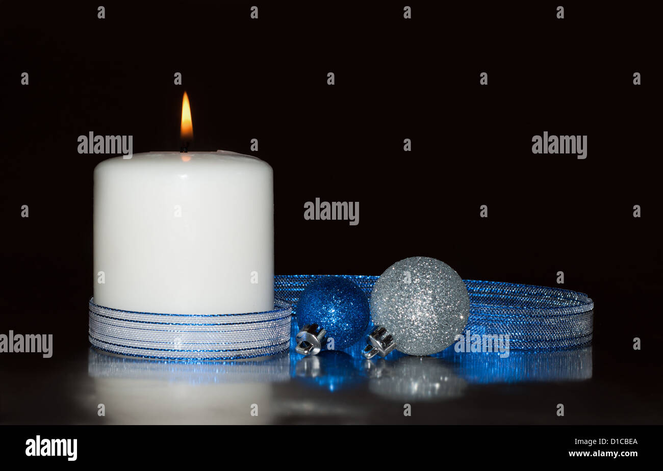 White Christmas candle con glittery baubles e un nastro blu contro uno sfondo scuro Foto Stock White Christmas candle con glittery baubles e un nastro blu contro uno sfondo scuro Foto Stock