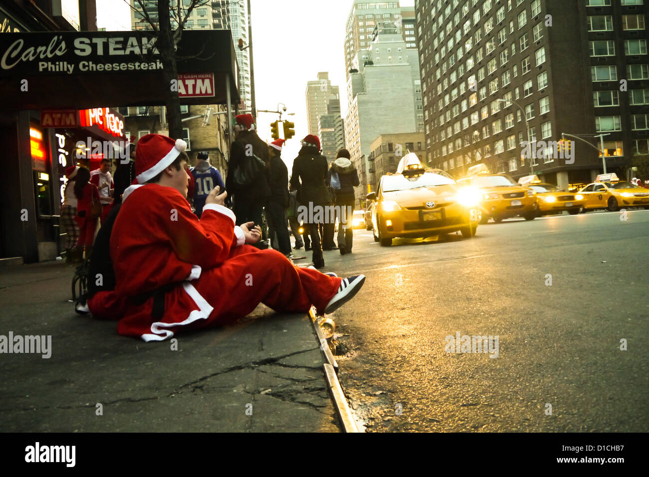 NEW YORK, NY - 15 dicembre: buontemponi vestiti da Babbo Natale sedersi sulla strada a riposo durante l'annuale evento SantaCon Dicembre 15, 2012 in New York City. (Foto di Donald Bowers) Foto Stock