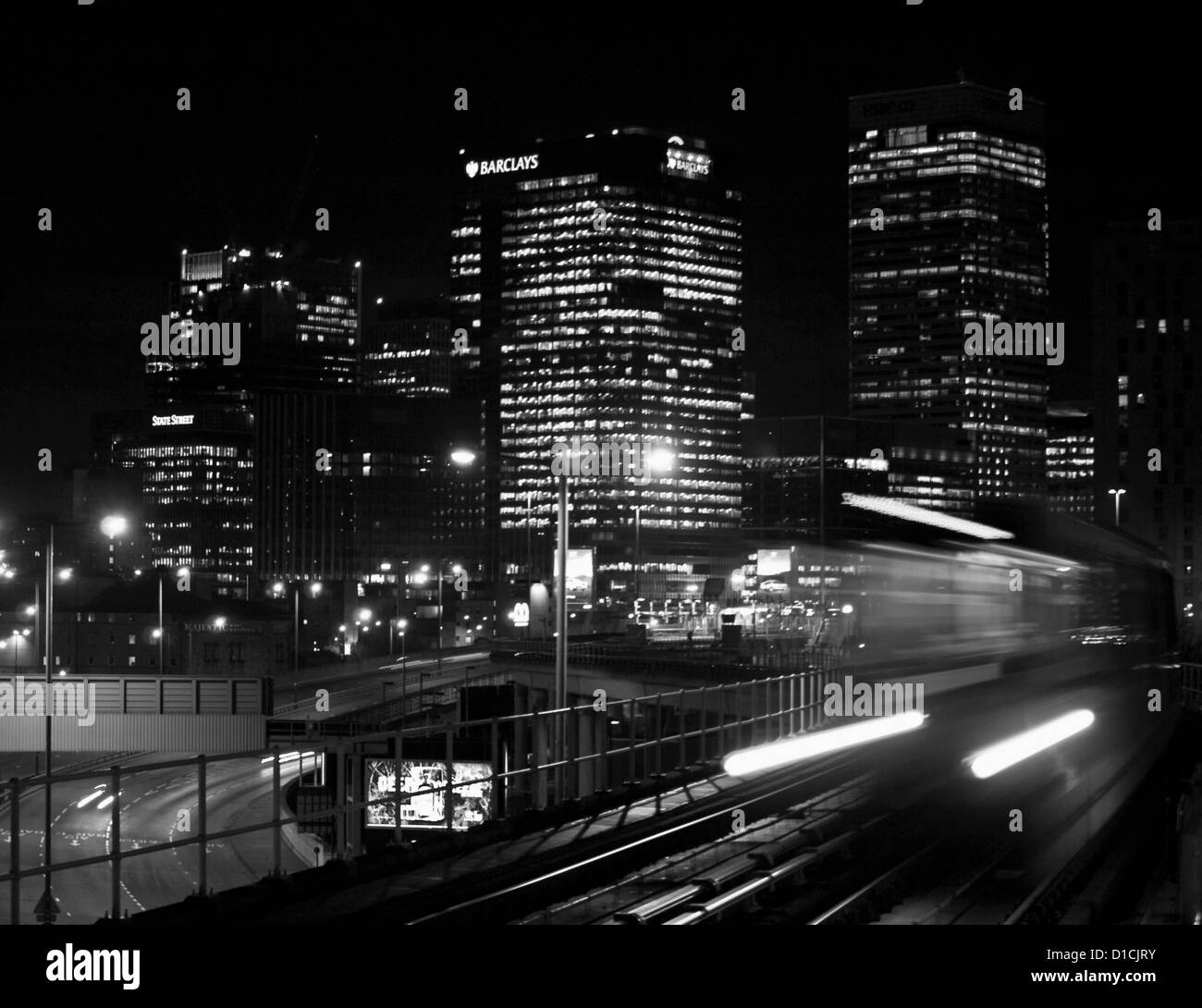 DLR treno arrivando a East India DLR station mostra Canary Wharf grattacieli in background, London, England, Regno Unito Foto Stock