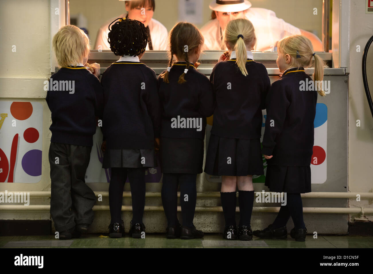 Scolari queuing per toast dopo mattina insieme alla Madonna e San Werburgh Cattolico della scuola primaria a Newcastle-under- Foto Stock