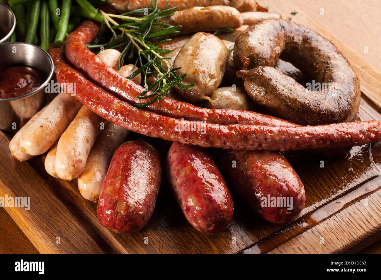 Assortimento di salsicce alla griglia su una tavola di legno. Foto Stock