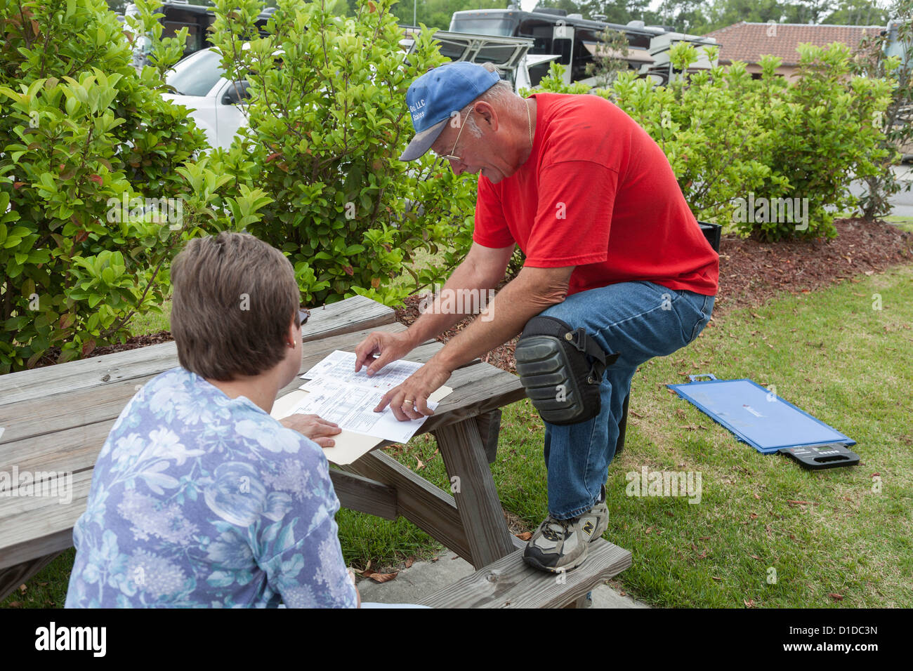 L'uomo recensioni pulmann resoconto di pesatura di documenti cartacei con la donna a RV resort in Brunswick, Georgia Foto Stock