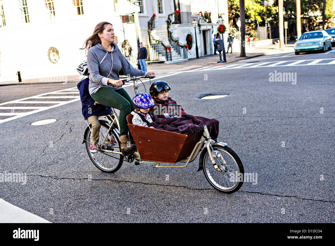 Una donna corse tre bambini sulla sua bicicletta cargo noto come un bakfiets a Charleston, Carolina del Sud. Foto Stock