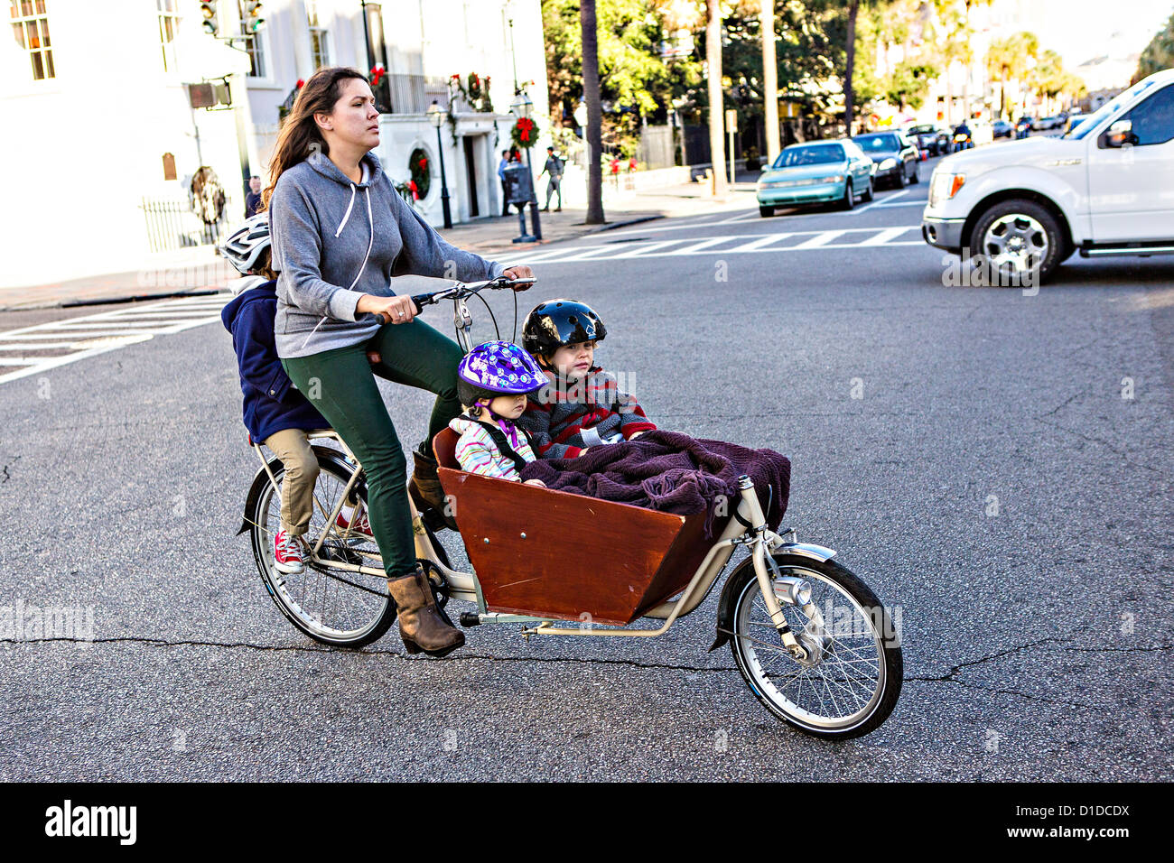 Una donna corse tre bambini sulla sua bicicletta cargo noto come un bakfiets a Charleston, Carolina del Sud. Foto Stock