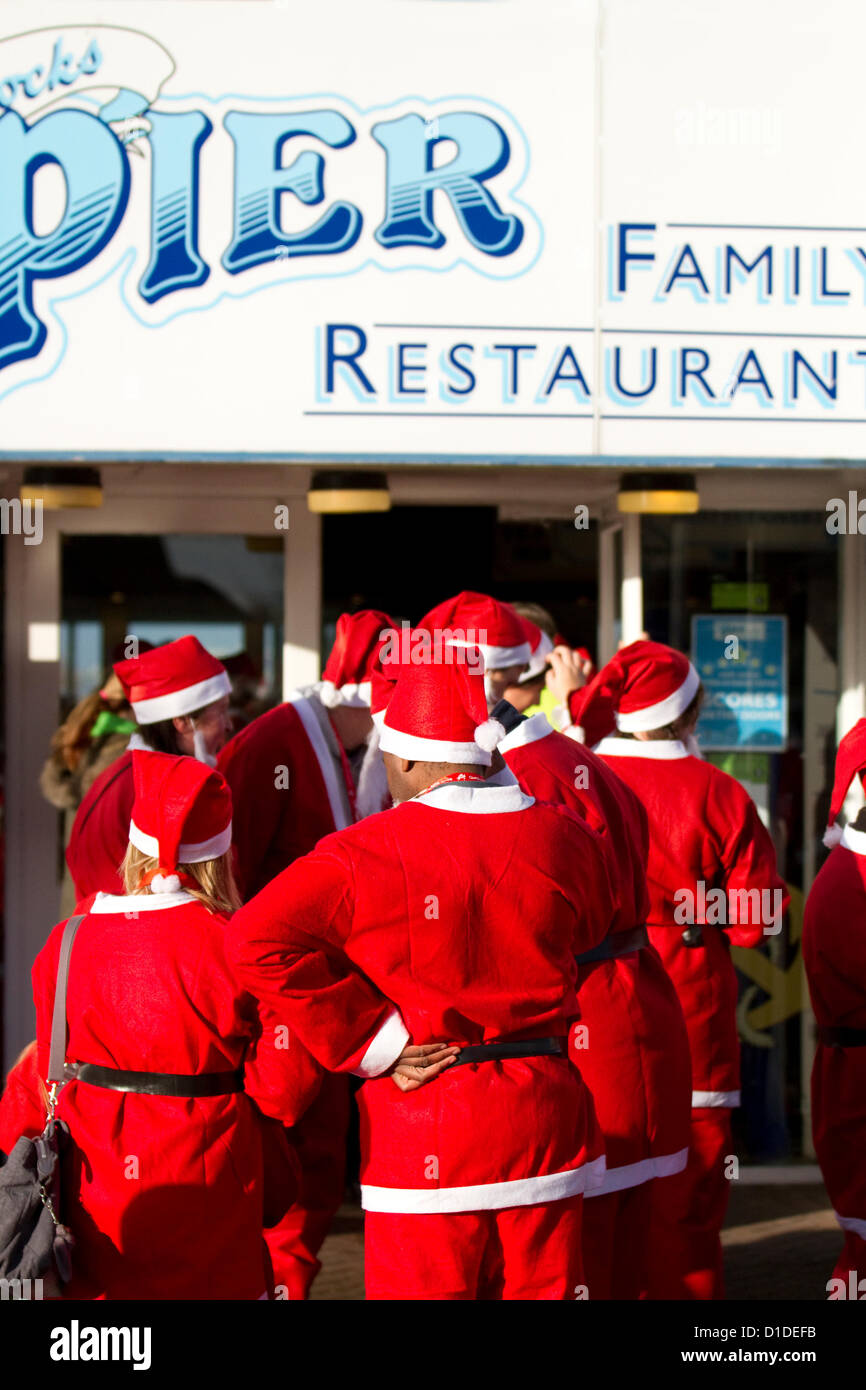 Pesce e Patatine fornitore, Chippy, pesce n' Chips, Southport, Merseyside Regno Unito domenica 16 dicembre, 2012. Guide in costume e partecipanti, stagionalmente vestiti da Babbo Natale, in Ospizio Queenscourt Christmas Santa Fun Run per la carità. Foto Stock