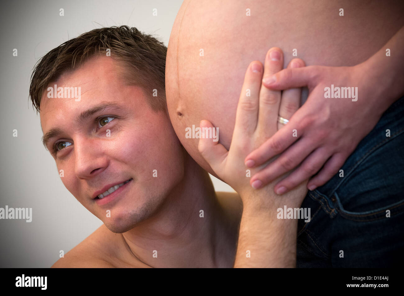 Un simbolico non datata immagine mostra un giovane uomo di intercettazioni attraverso il ventre di sua moglie incinta. Foto: Hans Wiedl - Modello rilasciato Foto Stock