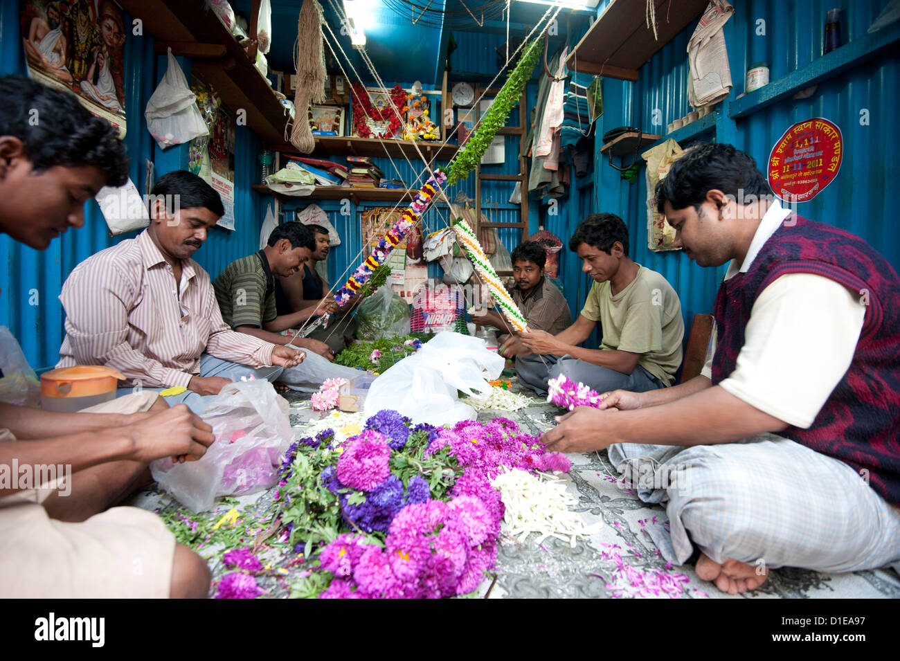 Mala maker (garland makers) al lavoro in Kolkata di mattina il mercato dei fiori, quella di Howrah, Calcutta, West Bengal, India, Asia Foto Stock