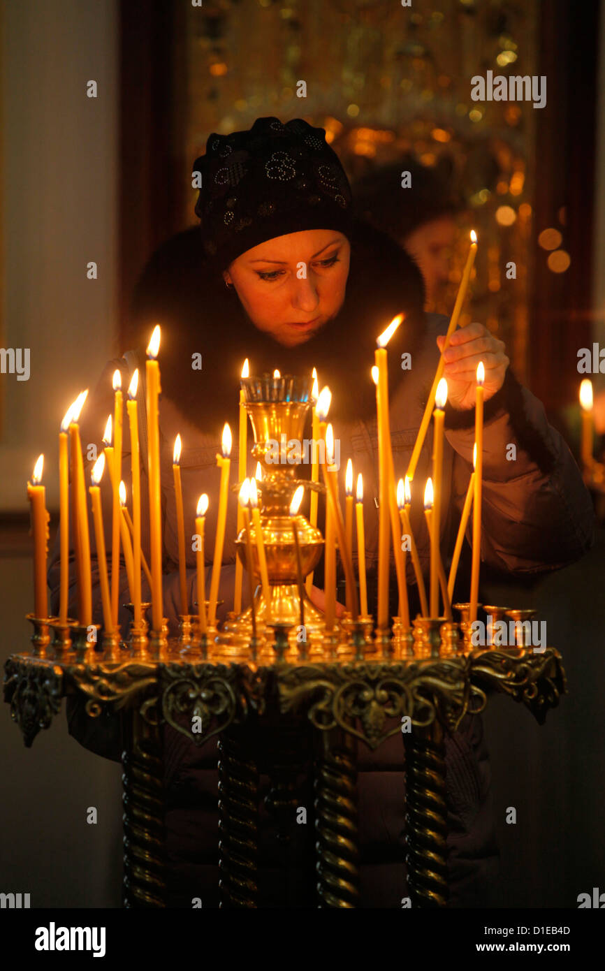 Donna accendere una candela, Trinità cattedrale, San Pietroburgo, Russia, Europa Foto Stock