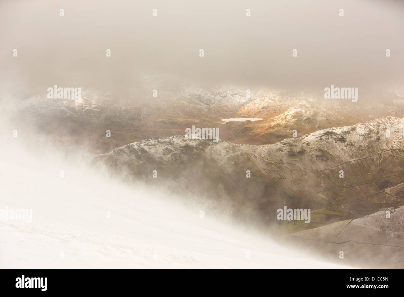 Guardando attraverso di Easdale Tarn da Fairfield in misty meteo con la tempesta di neve in alta venti, Lake District, UK. Foto Stock