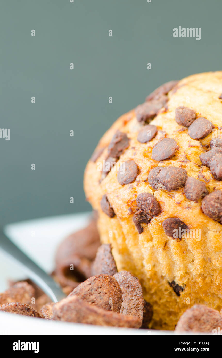 Un muffin e pezzetti di cioccolato su sfondo nero Foto Stock