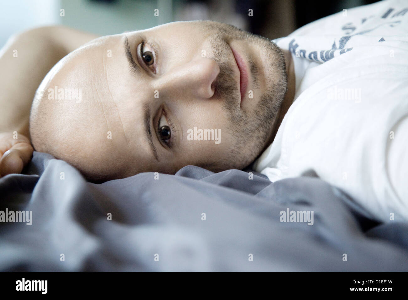 L'uomo con il designer stubbles giacente in letto, ritratto Foto Stock
