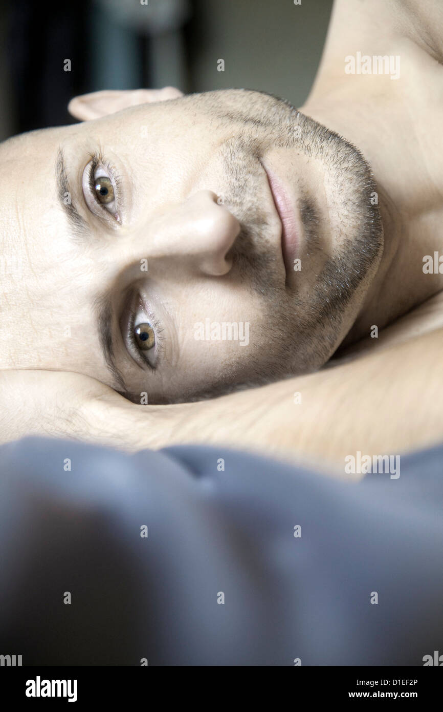 L'uomo con il designer stubbles giacente in letto, ritratto Foto Stock