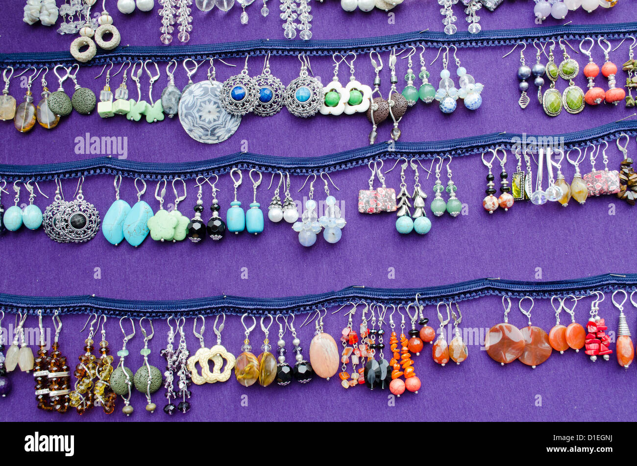 Colorati fatti a mano di varie forme decorative gioielli orecchini venduti in outdoor mercato equo. Foto Stock