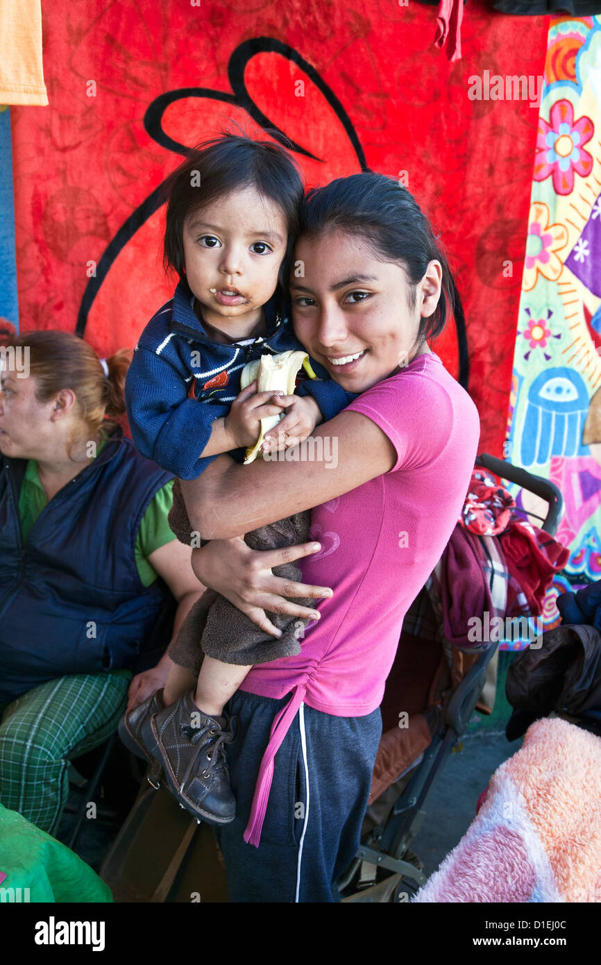 Bella sorridente giovane messicano ragazza con il suo bambino fratello che ha una bocca disordinato da mangiare banana Oaxaca de Juarez Mexico Foto Stock