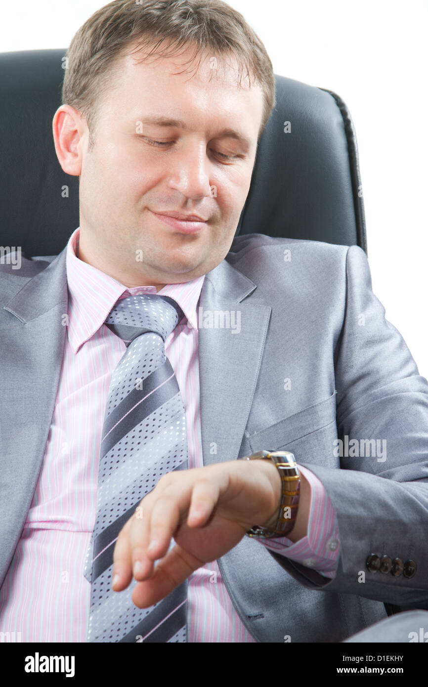 Close up ritratto di un bel giovane uomo d affari in un elegante completo guarda su guarda sulla sua mano isolato su bianco.Più di questo Foto Stock