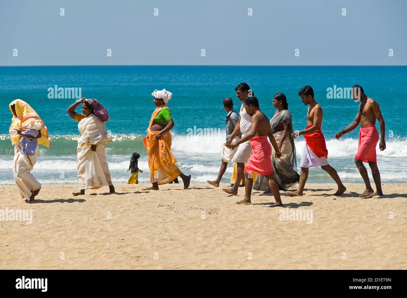 Ritratto orizzontale di un gruppo di Indiani a piedi lungo la spiaggia dopo aver eseguito puja (preghiere) a Varkala, Kerala. Foto Stock