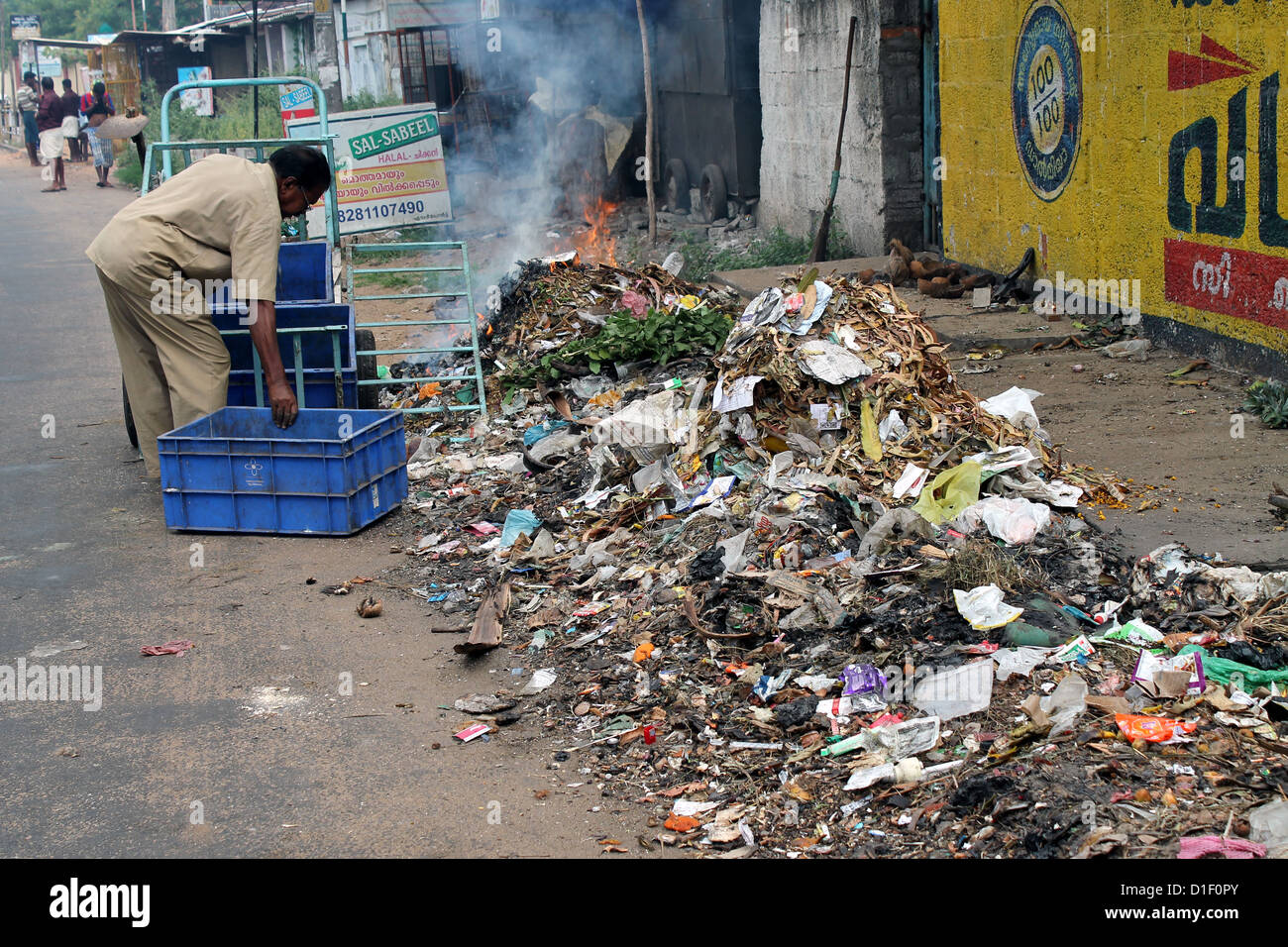Corporation dipendente impostando il fuoco ai rifiuti oggetto di pratiche di dumping su strada Foto Stock