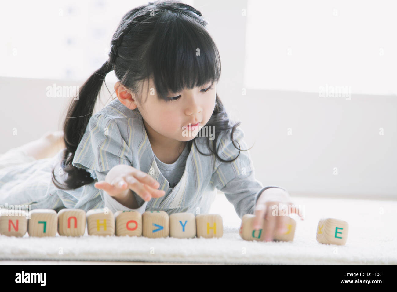 Età elementari ragazza che gioca con alfabeto di legno i cubi su pavimento Foto Stock
