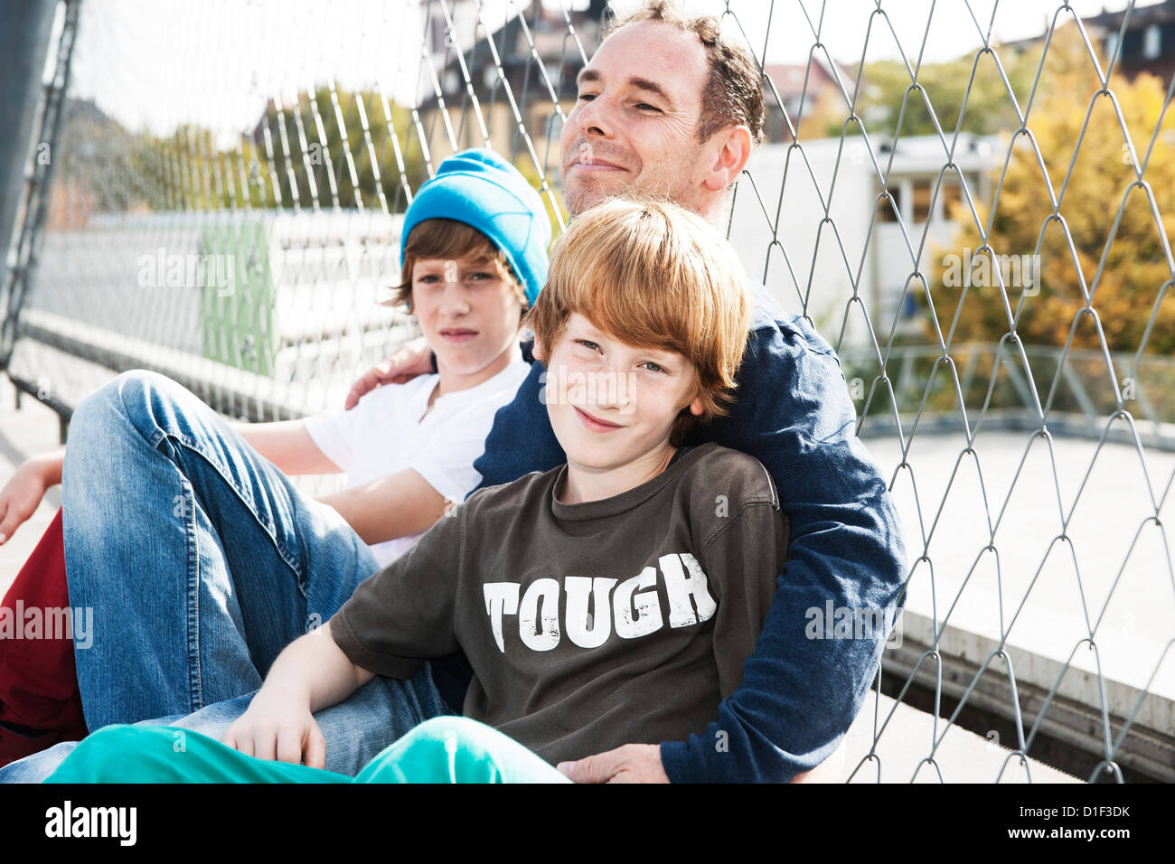 Padre e i due figli sul campo sportivo Foto Stock