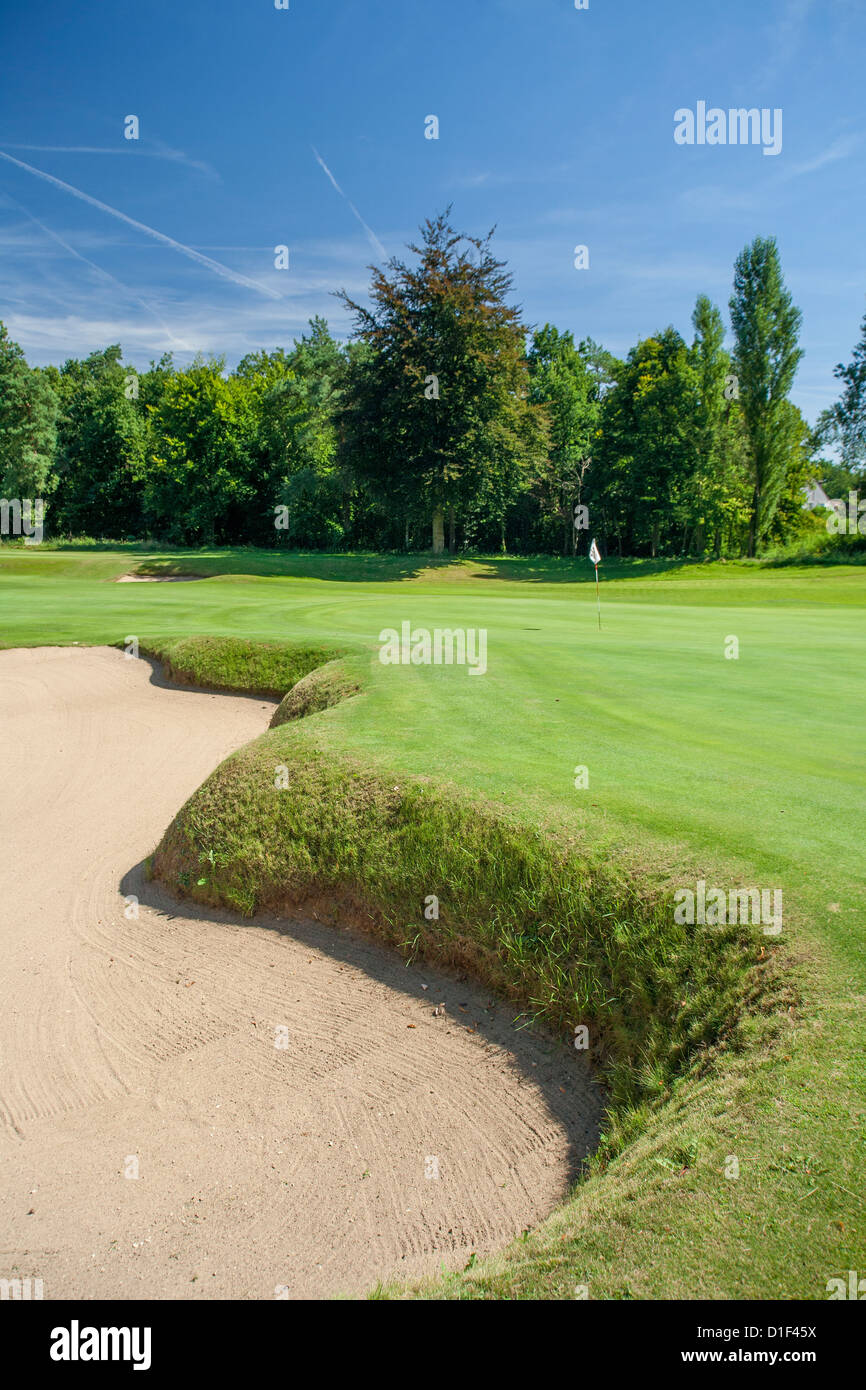 Bunker e green di golf con bandiera blu del cielo. Foto Stock