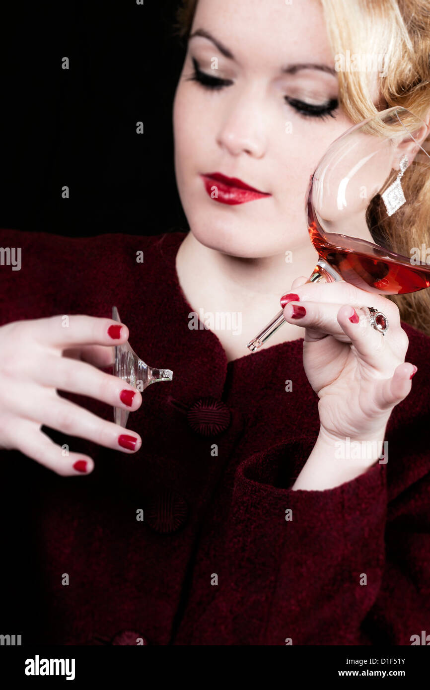 Una donna è in possesso di un vetro rotto di vino nelle sue mani Foto Stock